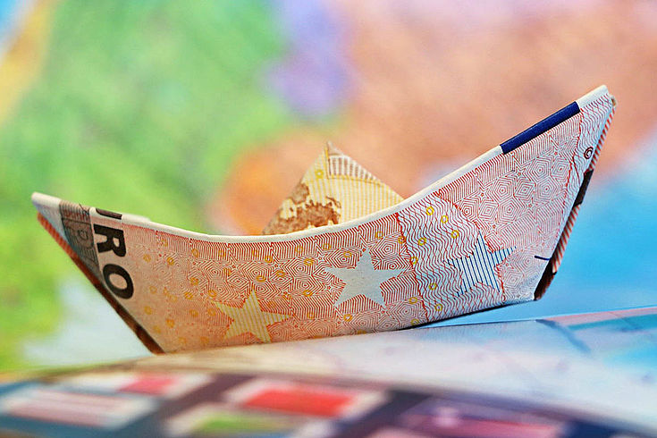 Ein Papierschiffchen aus einer Euro-Banknote gefaltet