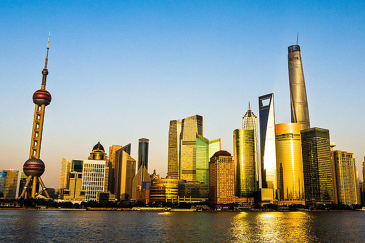 Skyline von ... Shanghai?... hohe Türme, Wolkenkratzer und ein spektakulärer Fernsehturm hinter einem Wasser.