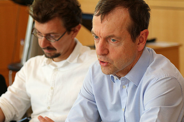 Erklärender Mann. Strenger Ausdruck. Gestikuliert.