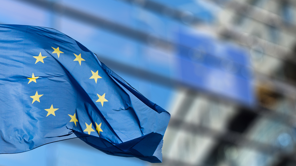 Wehende Europaflagge, im Hintergrund ist die Zentrale der Europäischen Union in Brüssel zu sehen.