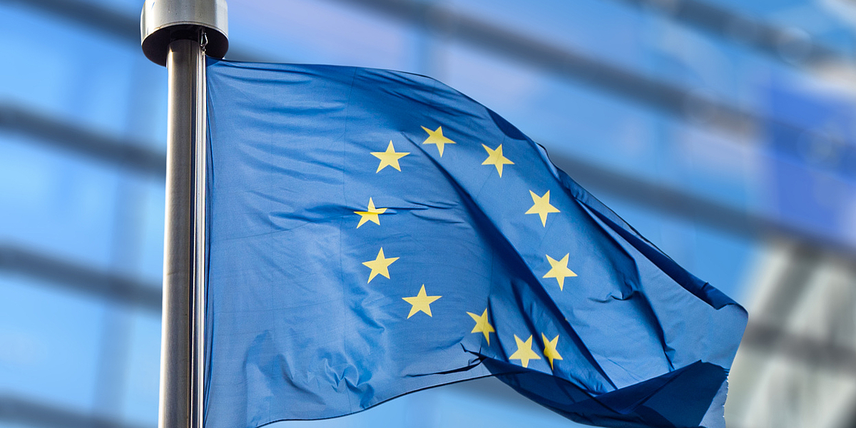Wehende Europaflagge, im Hintergrund ist die Zentrale der Europäischen Union in Brüssel zu sehen.