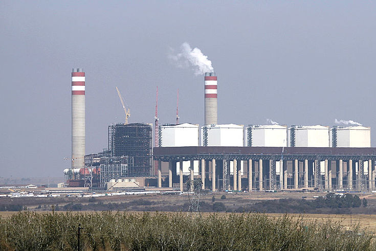 Ein Kraftwerk mit Schornsteinen aus denen Rauch aufsteigt.