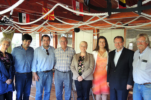 Dr Luther und Dr. Witterauf stehen mit einigen Mitgliedern des Projektpartners der HSS, Sirve a Chile, halbrund aufgestellt in einer Mehrzweckhalle