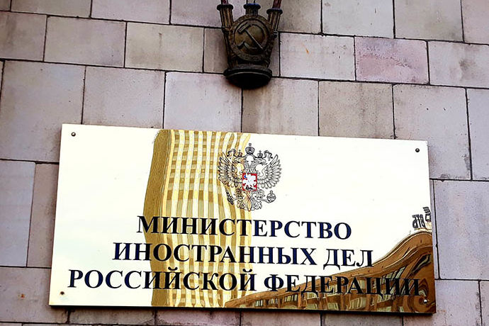 Wertig aussehende Plakette vor der Tür des russischen Aussenministeriums in der sich ein Büroturm spiegelt.