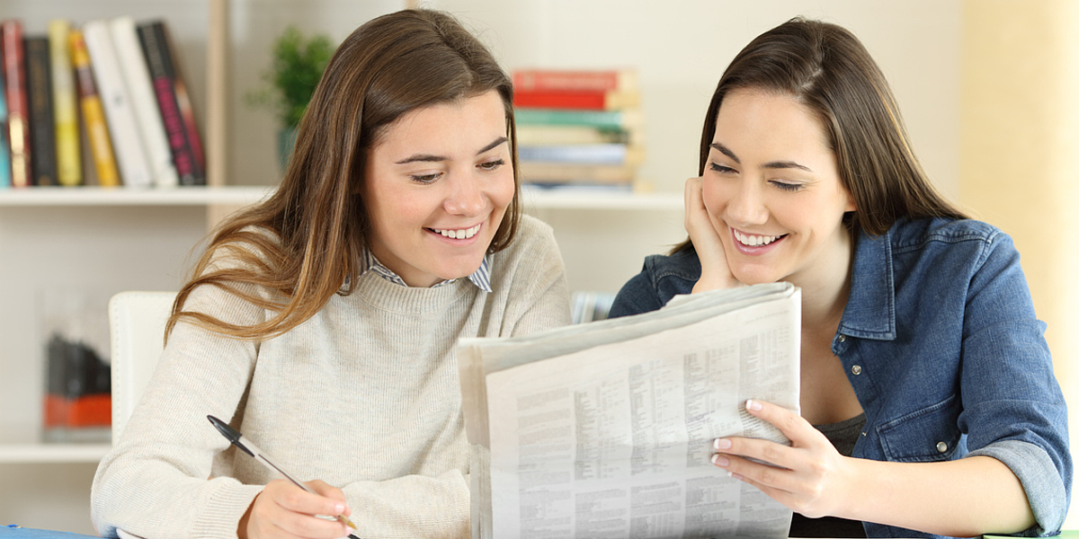 Zwei junge Frauen lesen gemeinsam eine Zeitung