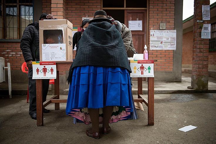 Eine Frau mit traditioneller Kleidung und Hut gibt ihre Stimme im Wahllokal ab.