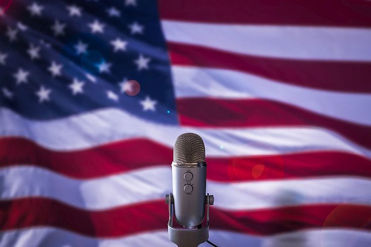 Die amerikanische Flagge weht hinter einem einsamen Mikrofon.