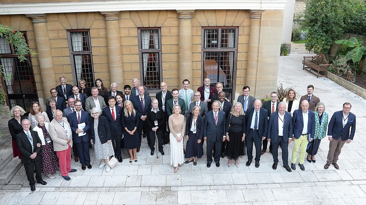 Eine große Gruppe, von circa 40 Teilnehmern, steht vor dem Eingang des historischen Konferenzgebäudes.