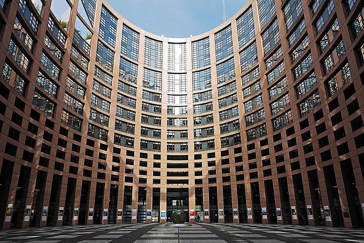 Das Parlament in Brüssel von außen. Viele Fenster, die in einen ovalen Innenhof blicken.