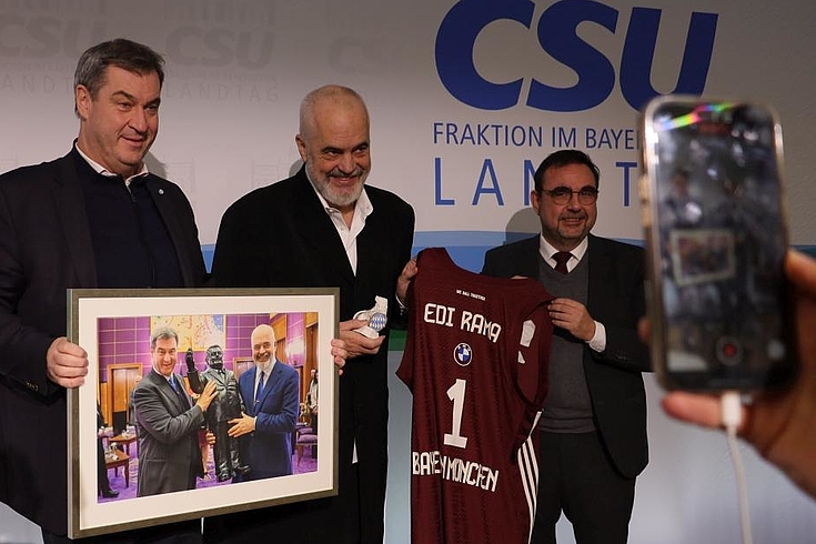 Söder hält ein Bild der Übergabe des FJS-Statue. Neben ihm freut sich Edi Rama über sein Trikot.