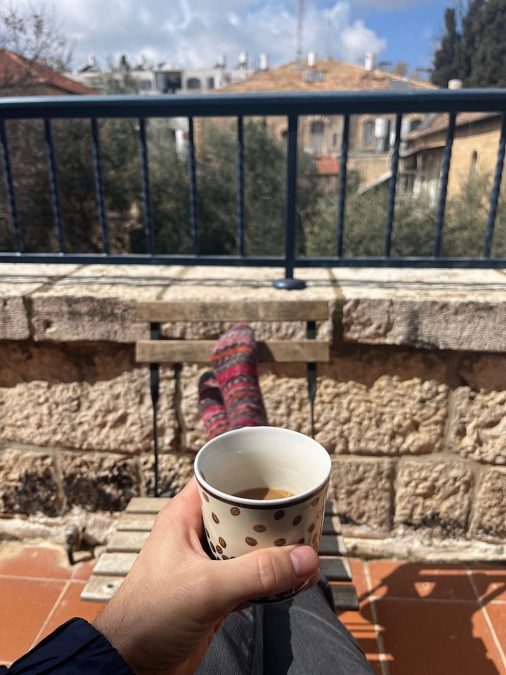Steffen Kudella hält eine Kaffeetasse in der Hand auf dem Balkon seiner Wohnung