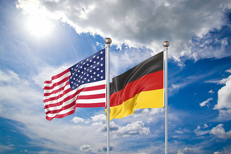 Die beiden Flaggen der USA und Deutschlands wehen nebeneinander im Wind