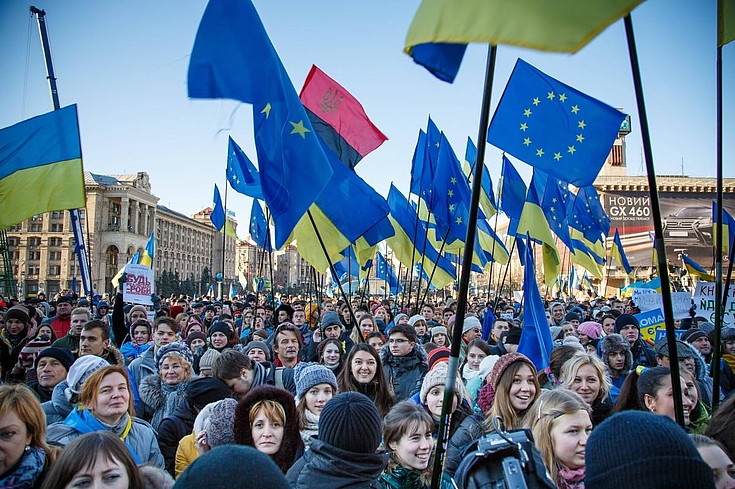 Demonstration mit vielen jungen Menschen, die Flaggen der Ukraine und der EU schwenken.