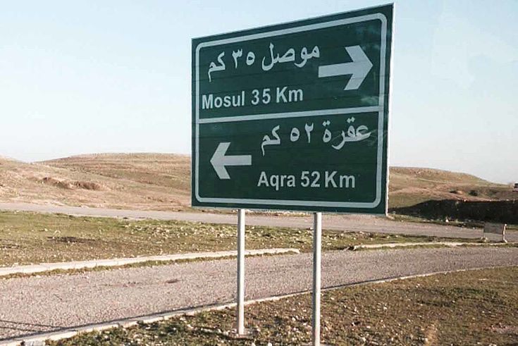 Straßenschild in der Wüste. Nach Mossul rechts, 31 KM. Nach Aqra, links, 52 Km.