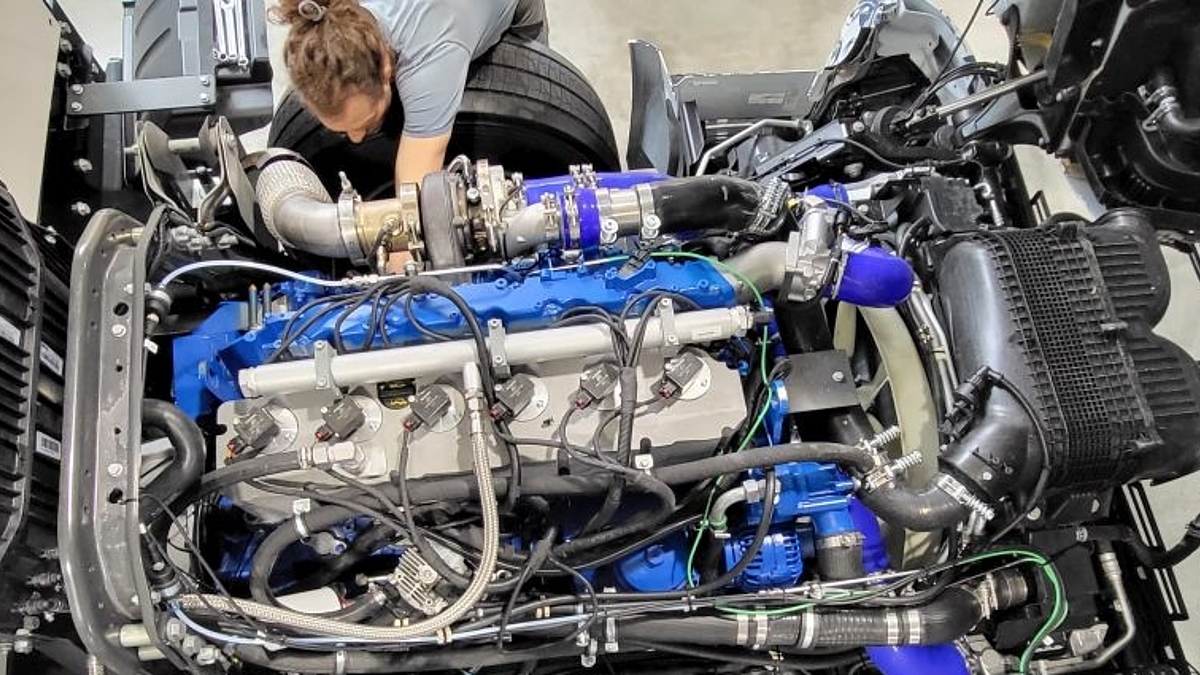Ein Wasserstoffmotor der KEYOU GmbH wird von einem Mitarbeiter in einen LKW eingebaut.

