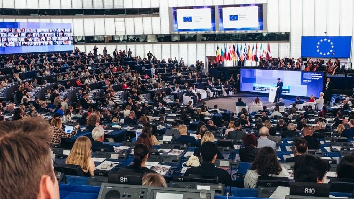 Das Europaparlament. Wir sitzen oben im Saal. Vor uns lauter nach vorne absinkende Hinterköpfe.
