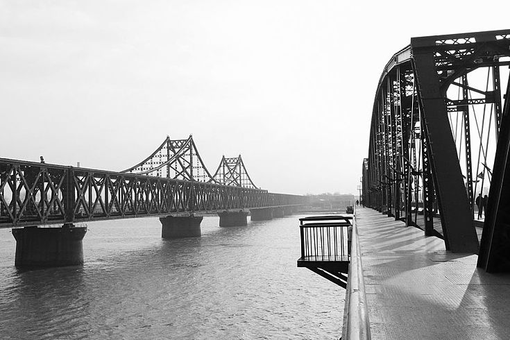 altmodische Brücke aus Stahlträgern, die einen breiten Fluss überspannt