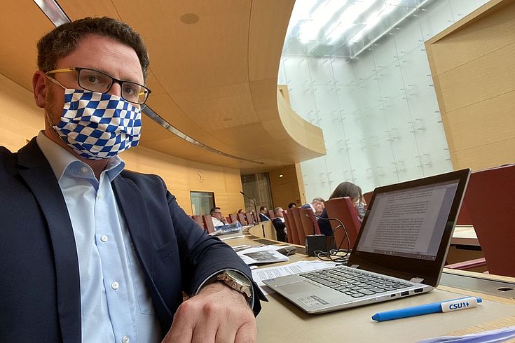 Hopp im Anzug allerdings ohne Krawatte aber mit Mund-Nasenschutz auf seinem Platz im Bayerischen Landesparlament