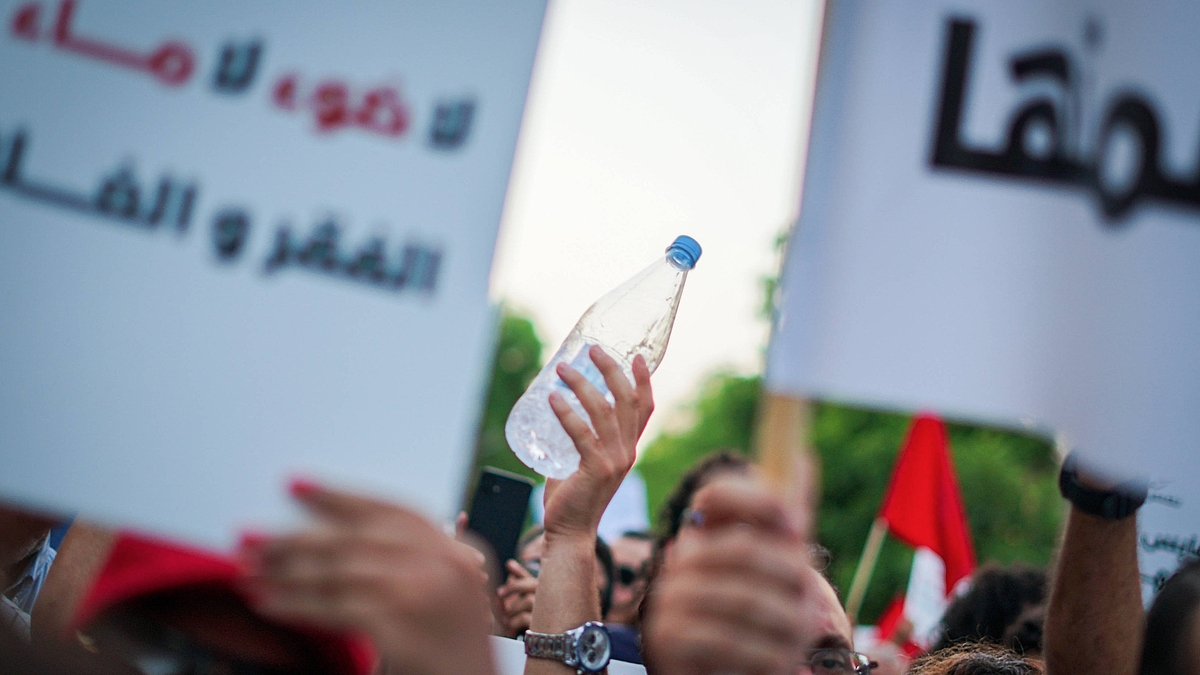 Demonstration in Tunis, Tunesien, bei der Plakate und Wasserflaschen hochgehalten werden. 