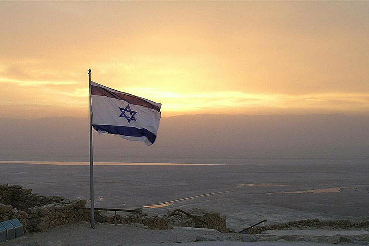 Israelische Flagge mit dem Davidsstern weht über einer weiten Ebene im Abend/Morgenlicht