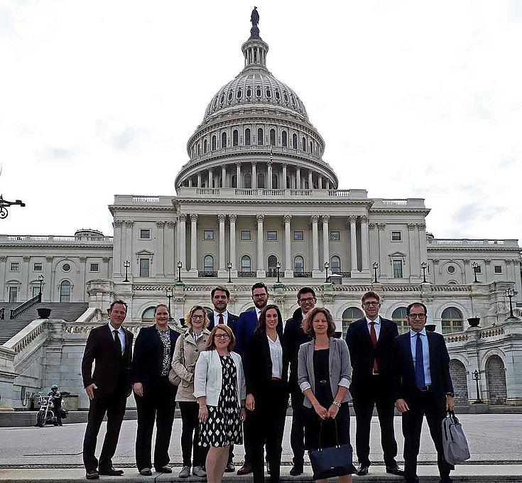 Gruppenbild vor dem US-Kongress in Washington. Ein gewaltiger Sandsteinbau mit Säulen und Kuppel, architektonisch angelehnt an den Petersdom in Rom.