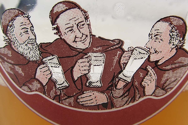 Drei fröhliche Mönche trinken Bier aus halbleeren Krügen.