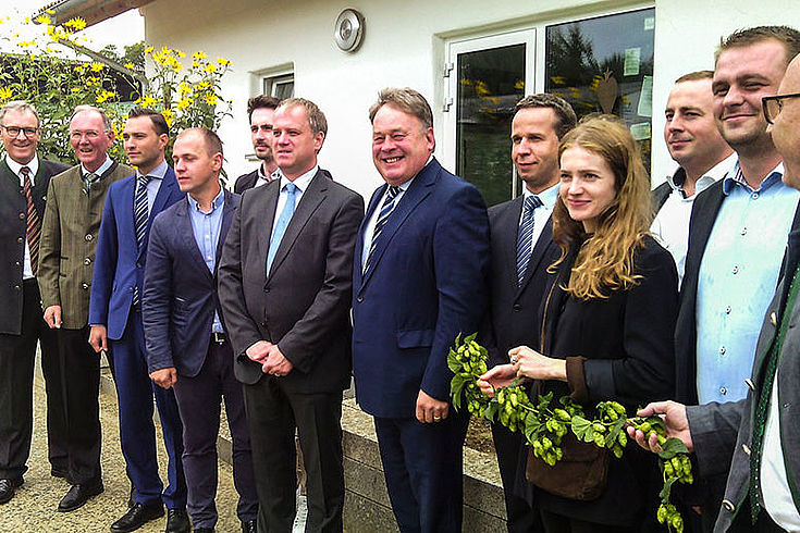 Die Besucher aus Rumänien stehen mit Staatsminister Brunner vor dem sogenannten Hopfenhaus in Steinbach