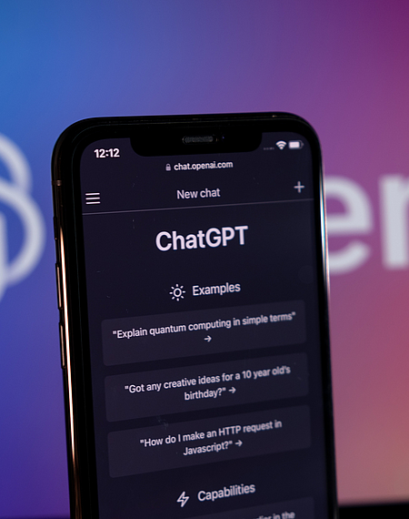 Smartphone zeigt den Schriftzug ChatGPT sowie einen aktuellen Chatverlauf