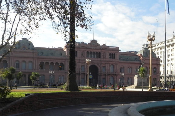 Die Casa Rosada, der argentinische Präsidentenpalast in der Hauptstadt Buenos Aires. Im Vordergrund ist ein Springbrunnen zu sehen. Dahinter ist der rosafarbene Palast.