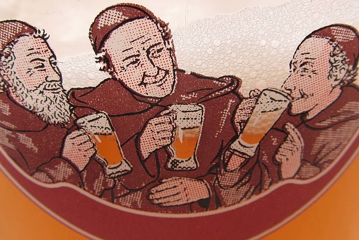 Drei fröhliche Mönche trinken Bier aus halbvollen Krügen