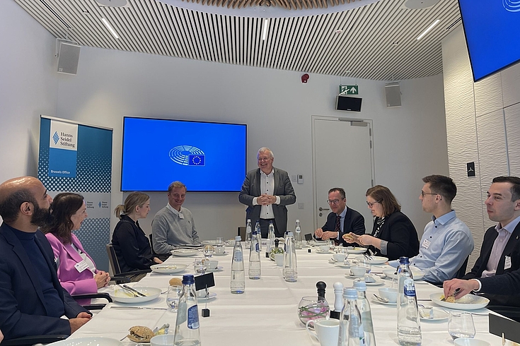 Markus Ferber, MdEP, (Mitte stehend) hält eine Rede vor den um einen Tisch versammelten Teilnehmenden des HSS-Nexus-Programms.