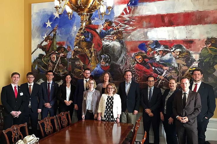 Gruppenbild mit Delegierten vor einem überdimensionalen Ölbild mit höchst amerikanischen Motiven. 