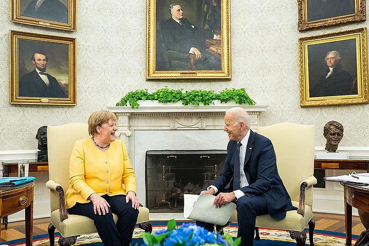 Merkel und Biden sitzen im Oval Office und lachen freundschaftlich