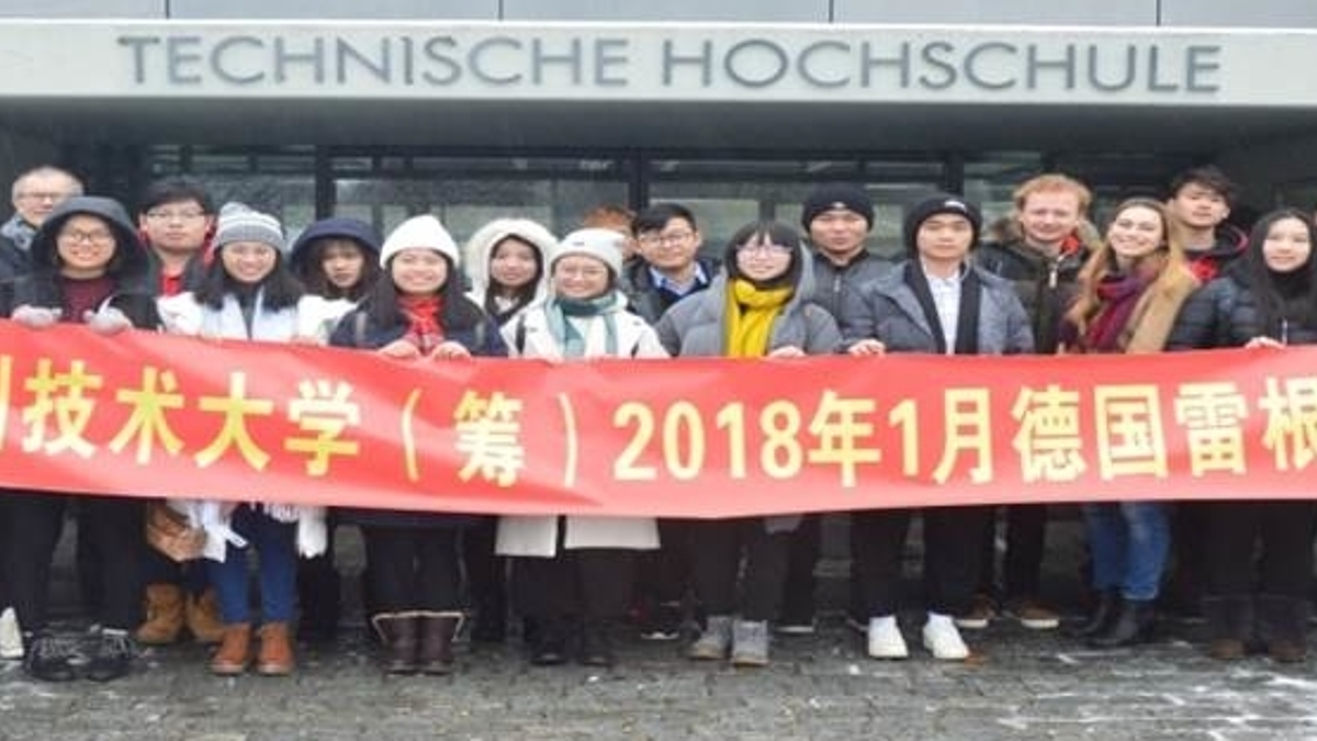 Eine Gruppe junger Chinesischer Studenten vor der Technischen Hochschule mit einem Banner mit Chinesischem Schriftzug darauf.