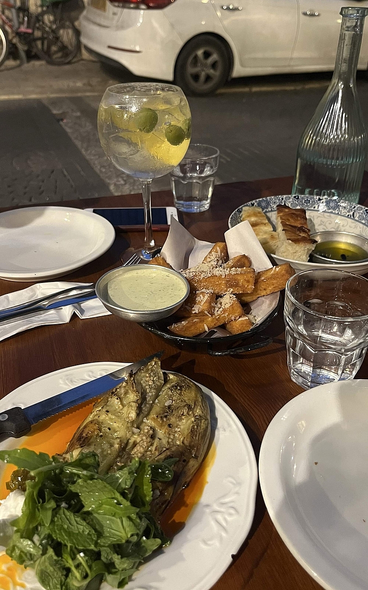 Ein Restaurant in einer Straße in Jerusalem, das auf die unterschiedliche Zubereitung von Auberginen spezialisiert ist: Es gibt sie gegrillt, gebacken oder als panierte Pommes, bestreut mit Parmesan; dazu wird ein Dip gereicht.