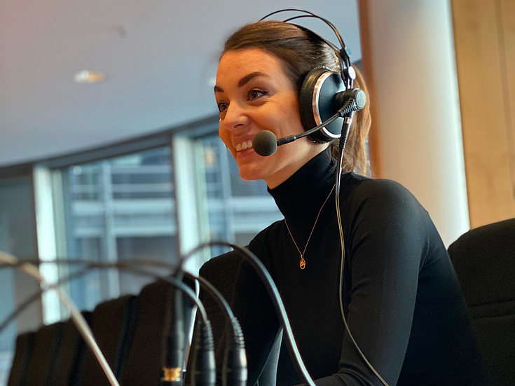 Frau mit Kopfhörer sitzt an einem Mischpult und nimmt Podcast auf