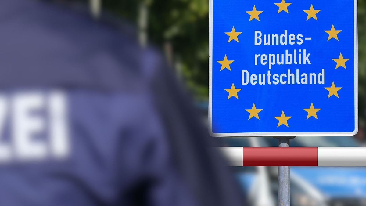 Ein Polizist steht an der deutschen Grenze vor dem Schild Bundesrepublik Deutschland