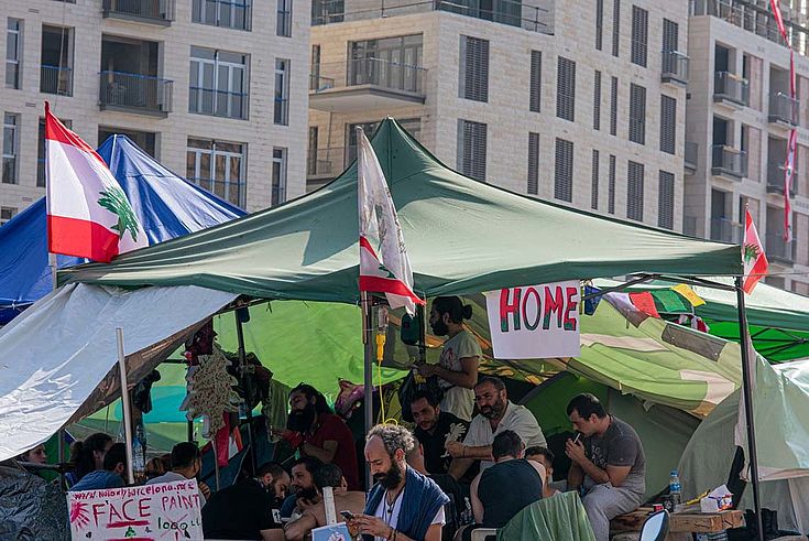 Zelte auf einer Straße in Beitrut. Wimpel und Spruchbänder, auf einem steht "home".