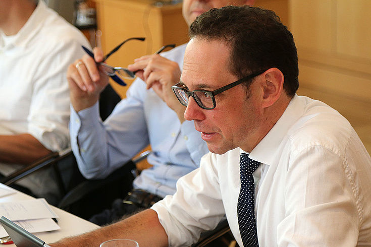 Engagierte Rede eines Mannes mit hochgekrempelten Ärmeln, Brille, Krawatte