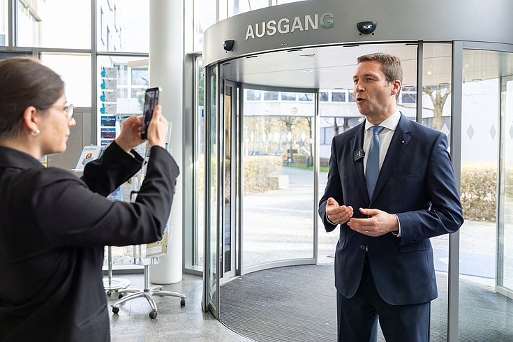 Matthias Dießl, Präsident des Sparkassenverbands Bayern, posiert für ein Handyfoto vor dem Eingang der Hanns-Seiddel-Stiftung