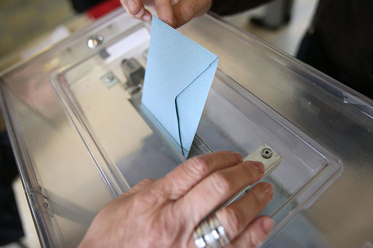 Hand, die Brief in eine Wahlurne wirft