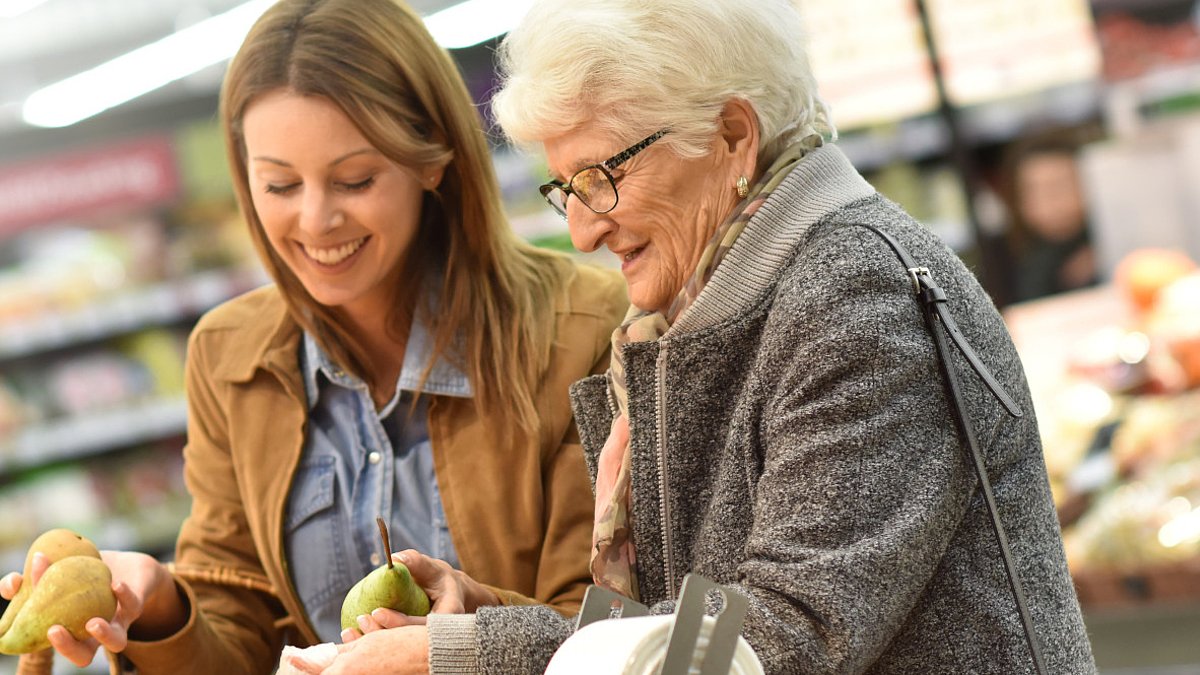 Jüngere Frau hilft älterer Dame beim Einkaufen
