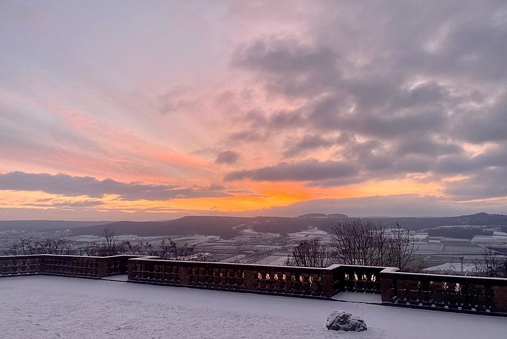 Blick in den Sonnenuntergang von der Maintalterrasse. Wolken treiben am Horizont.