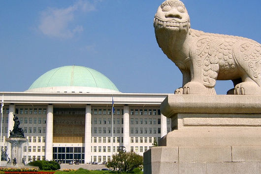 In Seoul steht vor dem niedrigen Parlamentsgebäude mit einer hellen grünen Kuppel eine Steinfigur mit dem Aussehen eines Fabelwesens 