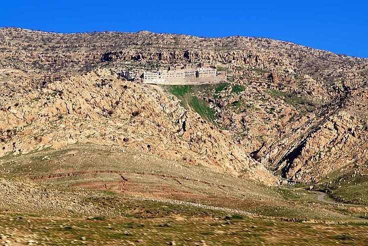 Ein Kloster drückt sich an die steilen Hänge eines staubigen Berges.