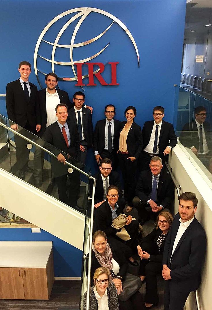 Delegierten auf einer Treppe mit Knick vor dem großen Logo der "IRI"