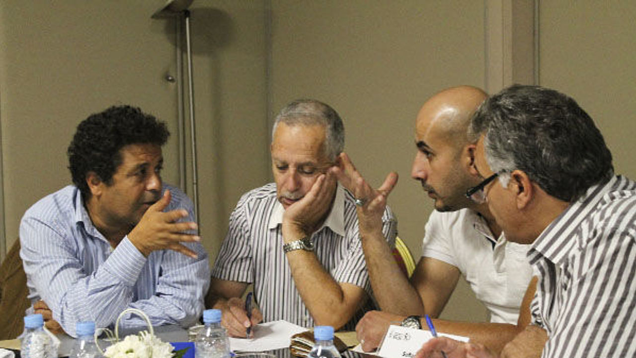 Vier Männer an einem Tisch sind in ein angeregtes Gespräch vertieft